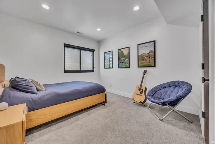 Bedroom featuring a window with integrated blinds, recessed lighting, white walls, and light-colored carpet flooring