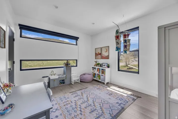Room featuring light wood-finish flooring, white walls, recessed lighting, and contemporary black-framed windows