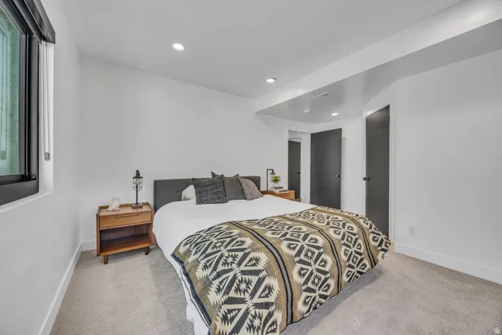 Bedroom featuring recessed lighting, light-toned carpet flooring, and a large window with roller shades