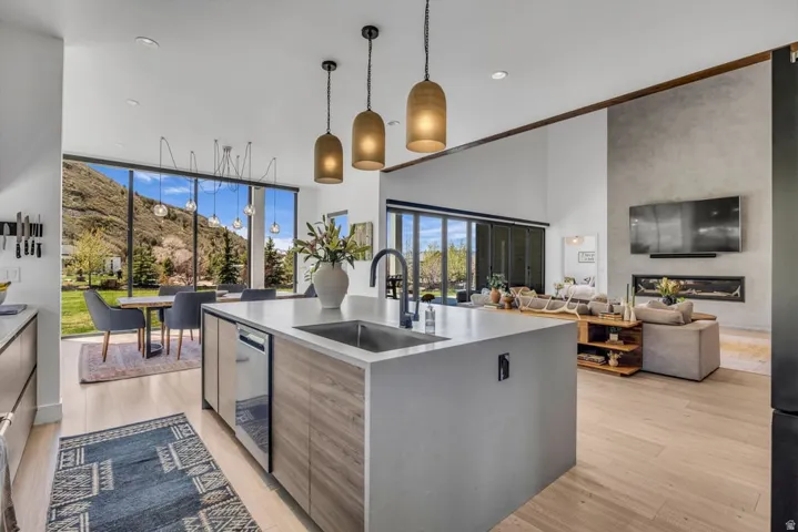 Open-concept kitchen featuring a large island with an undermount sink, light wood-finish cabinetry, and light-toned flooring