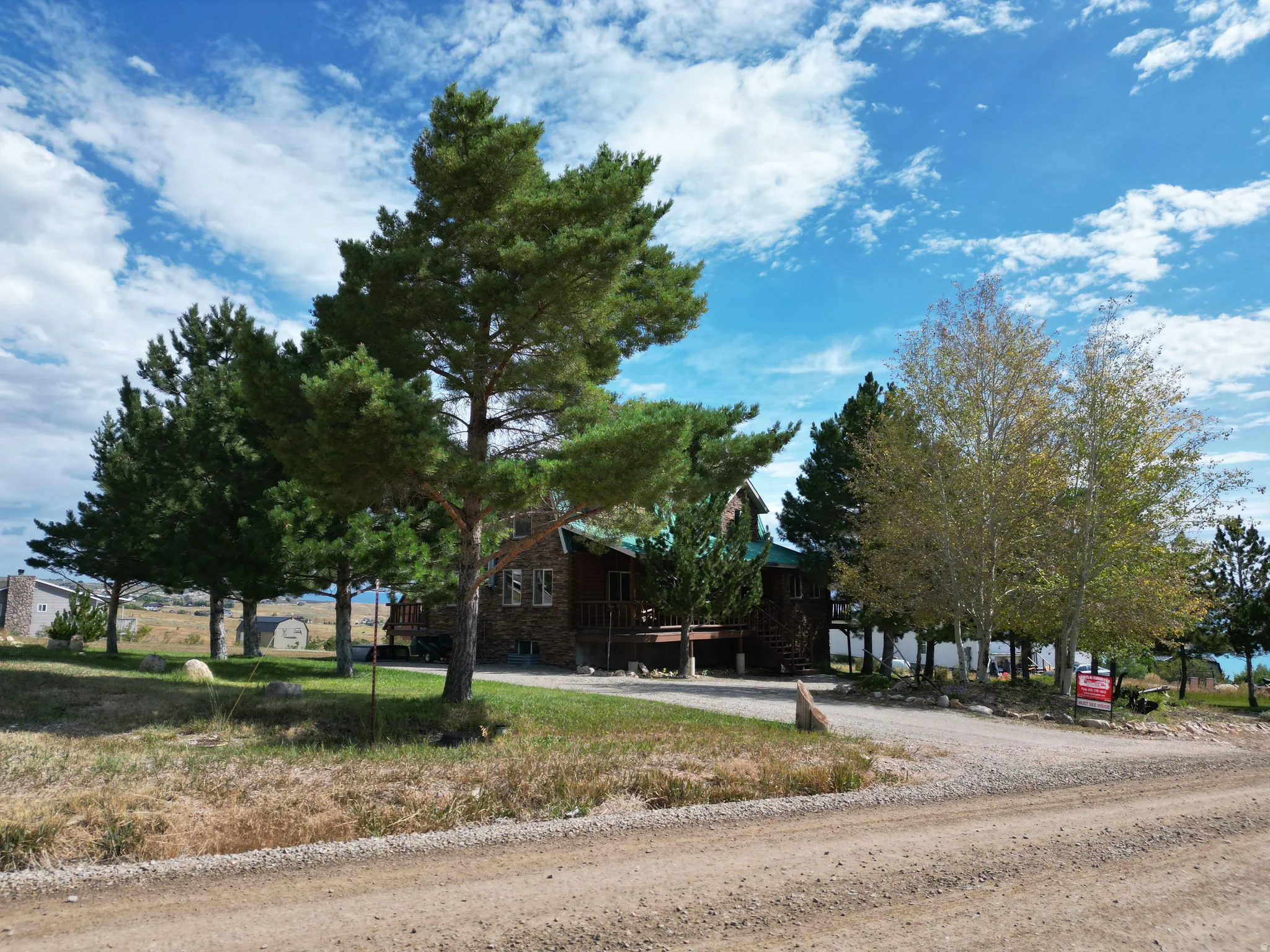 Log cabin exterior with a porch, surrounded by mature trees