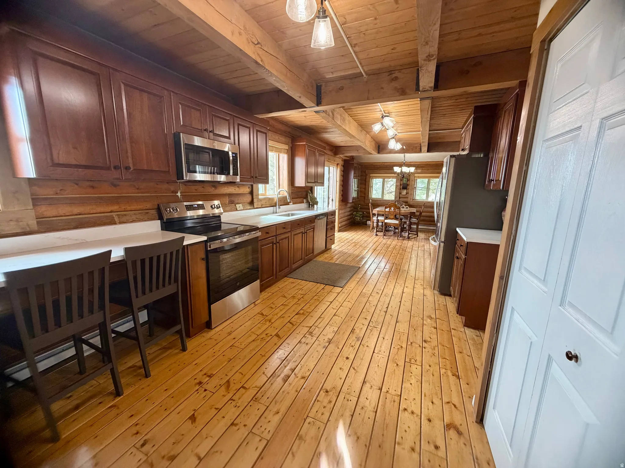Kitchen featuring wood-finish flooring, exposed wood beams, and log-style walls