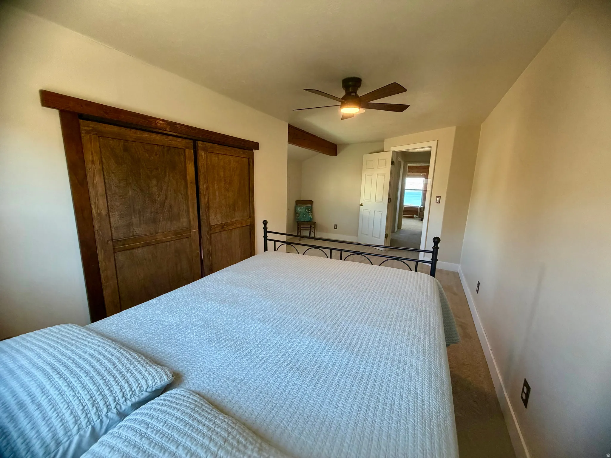 Recessed lighting, ceiling fan, wood-finish sliding closet doors, and wood-beam accents
