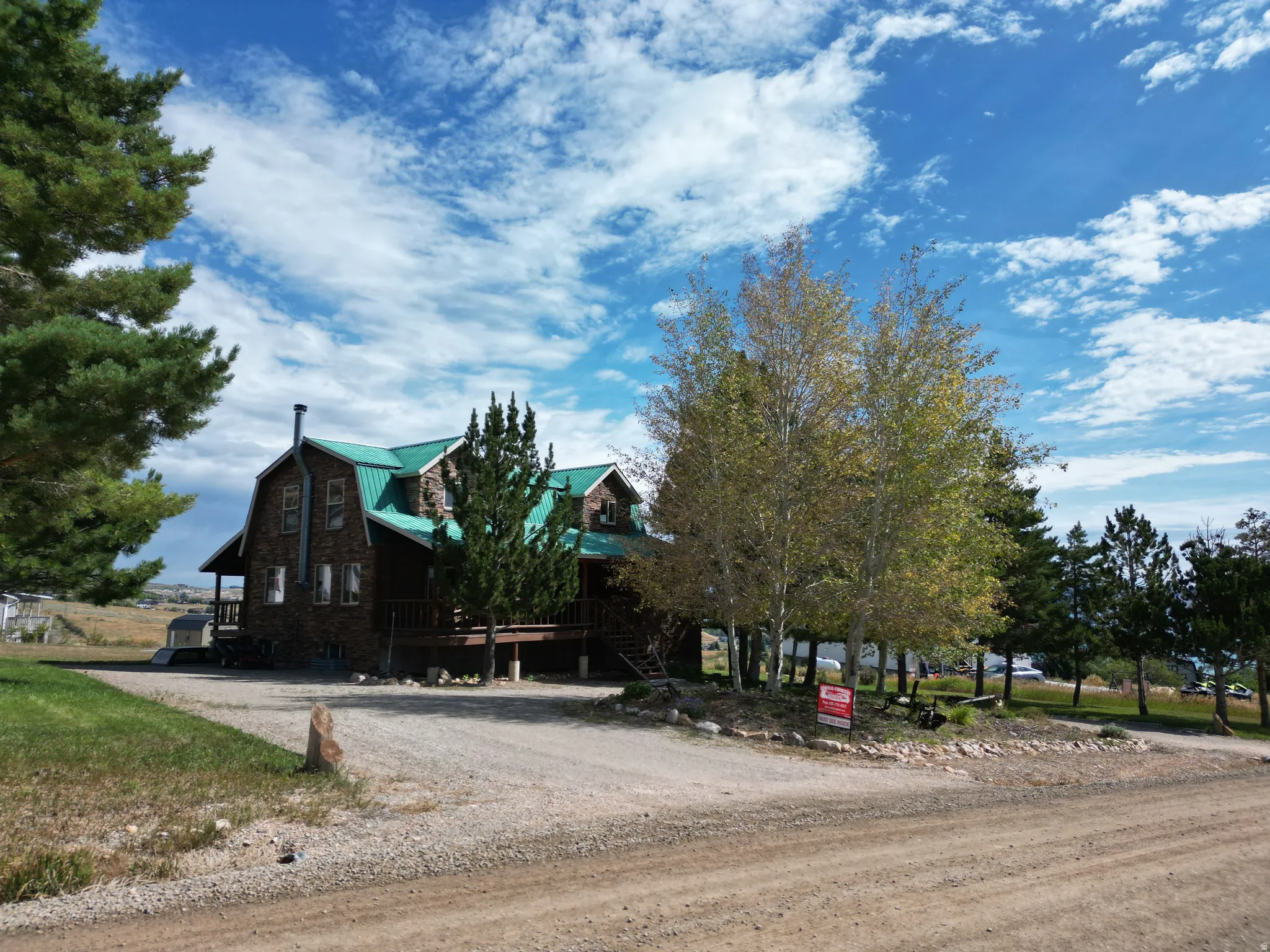 Barn-style home with a green metal roof and a stone facade
