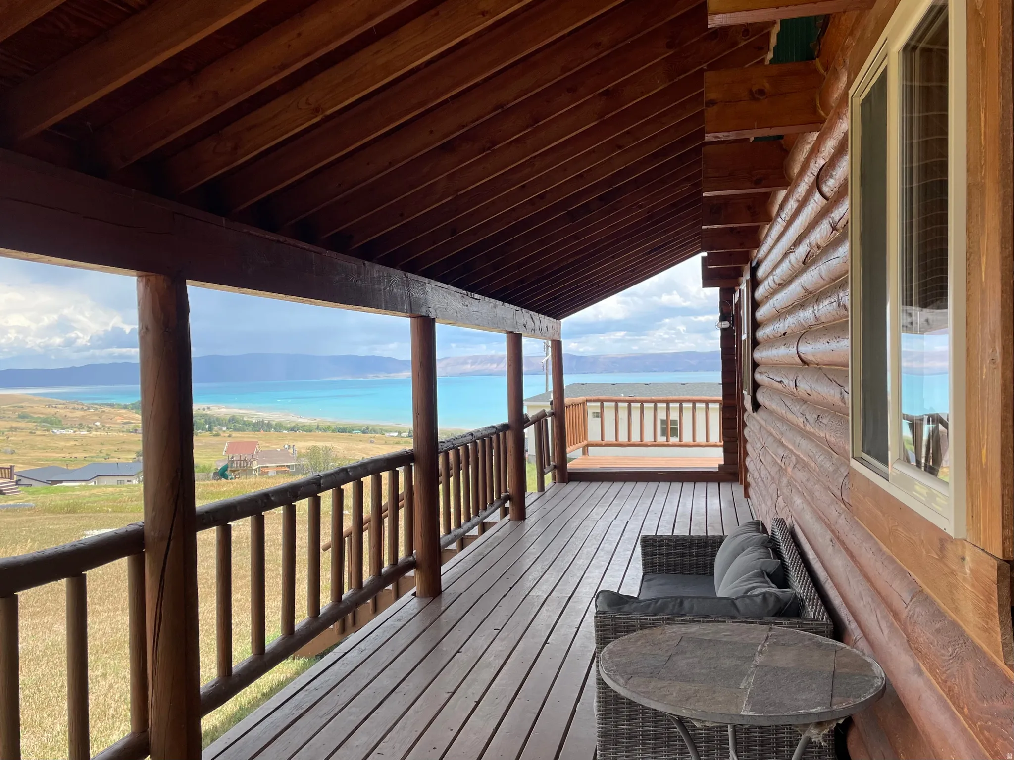 Expansive covered porch featuring a wood deck, log railings, and a log cabin exterior