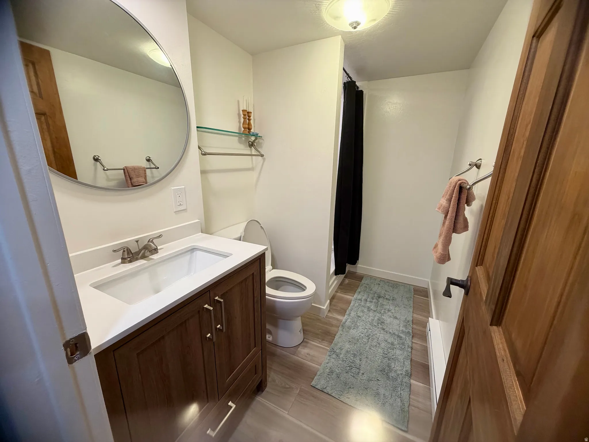 Bathroom featuring a wood-finish vanity with an integrated sink and light-toned countertop