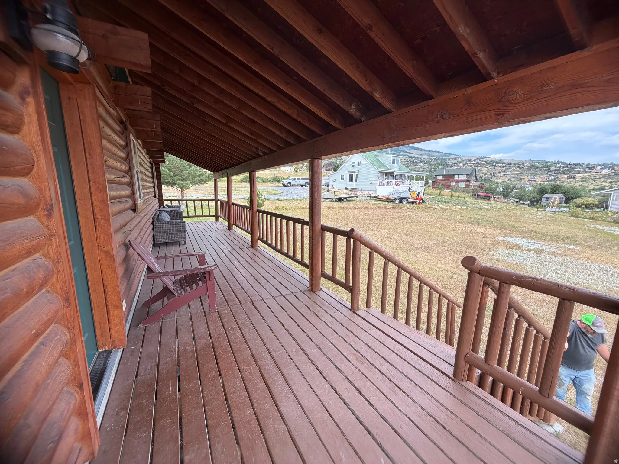 Expansive covered porch featuring a log cabin exterior, wood-finish decking, and rustic wood railings