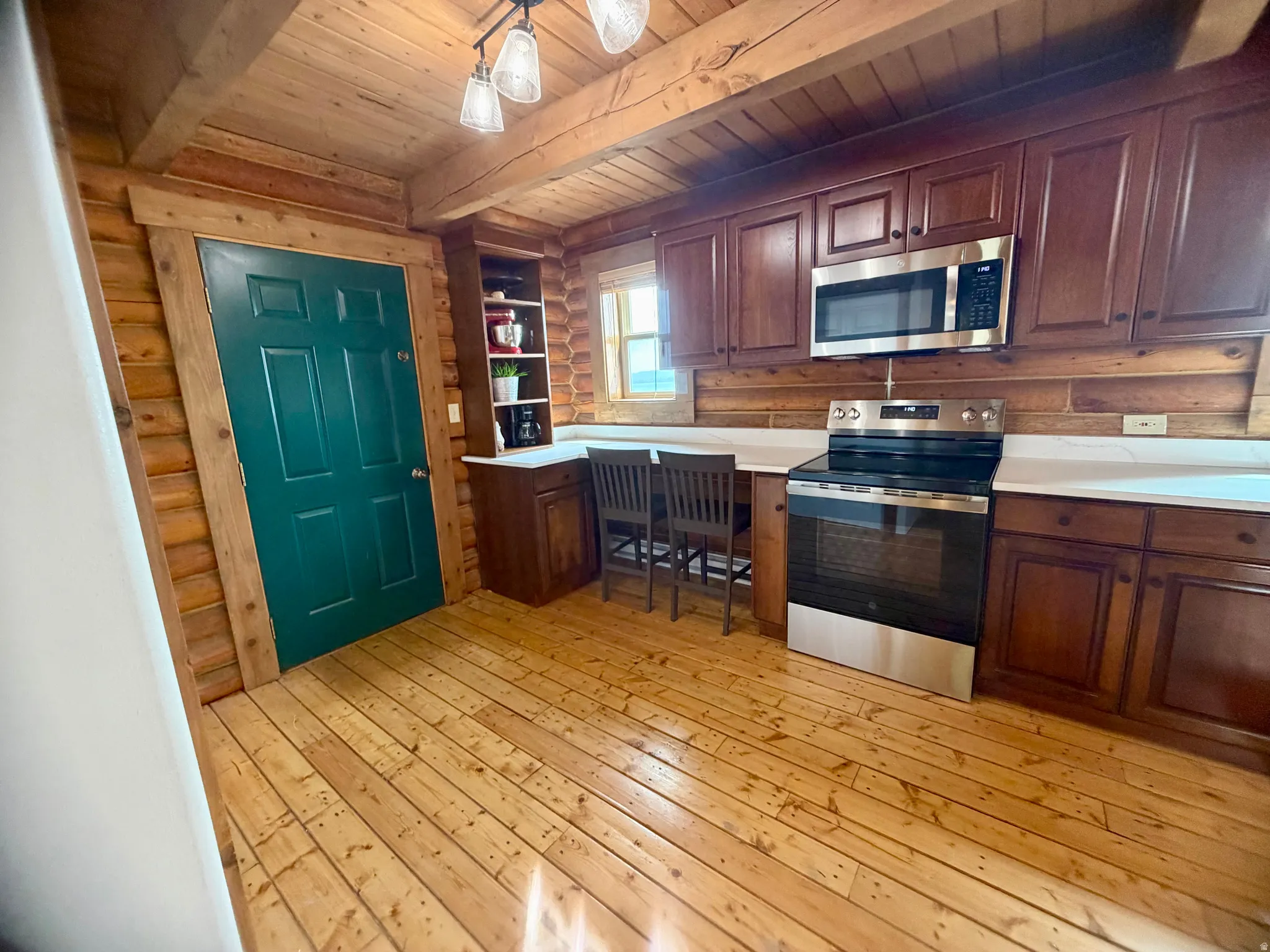 Log cabin interior featuring wood-finish flooring, exposed wood beam ceiling, and a green painted interior door