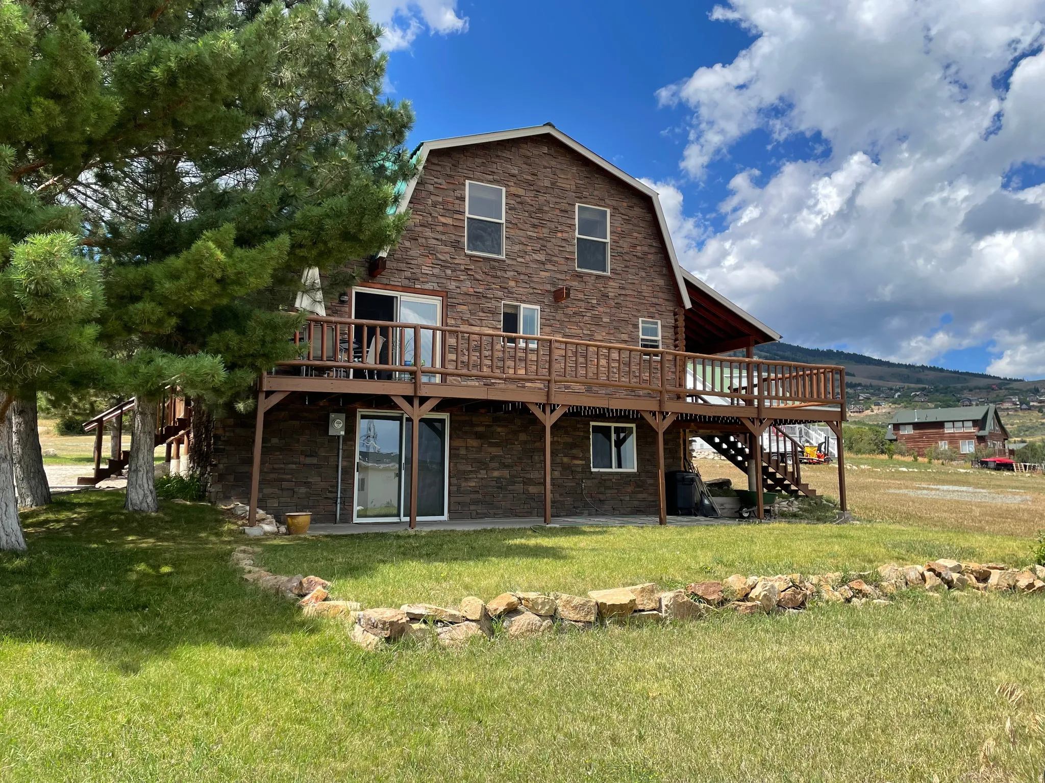 Stone veneer exterior with a gambrel roof and an expansive wood deck