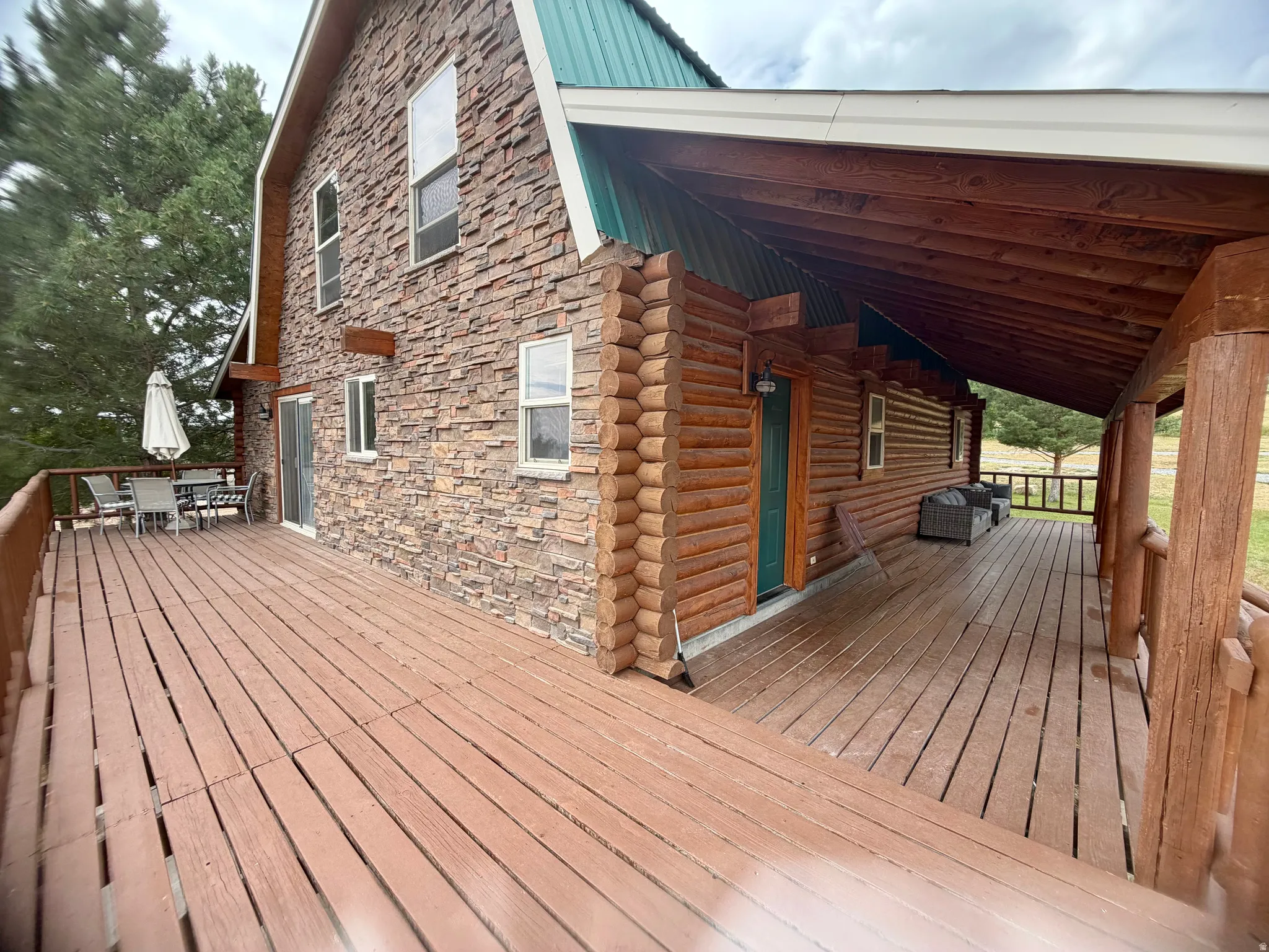 Expansive outdoor decking features a blend of log siding and stone veneer construction