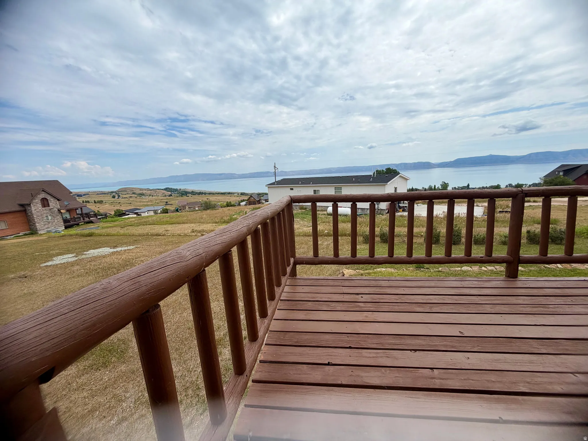 Expansive outdoor deck featuring wood-finish flooring and a rustic log railing