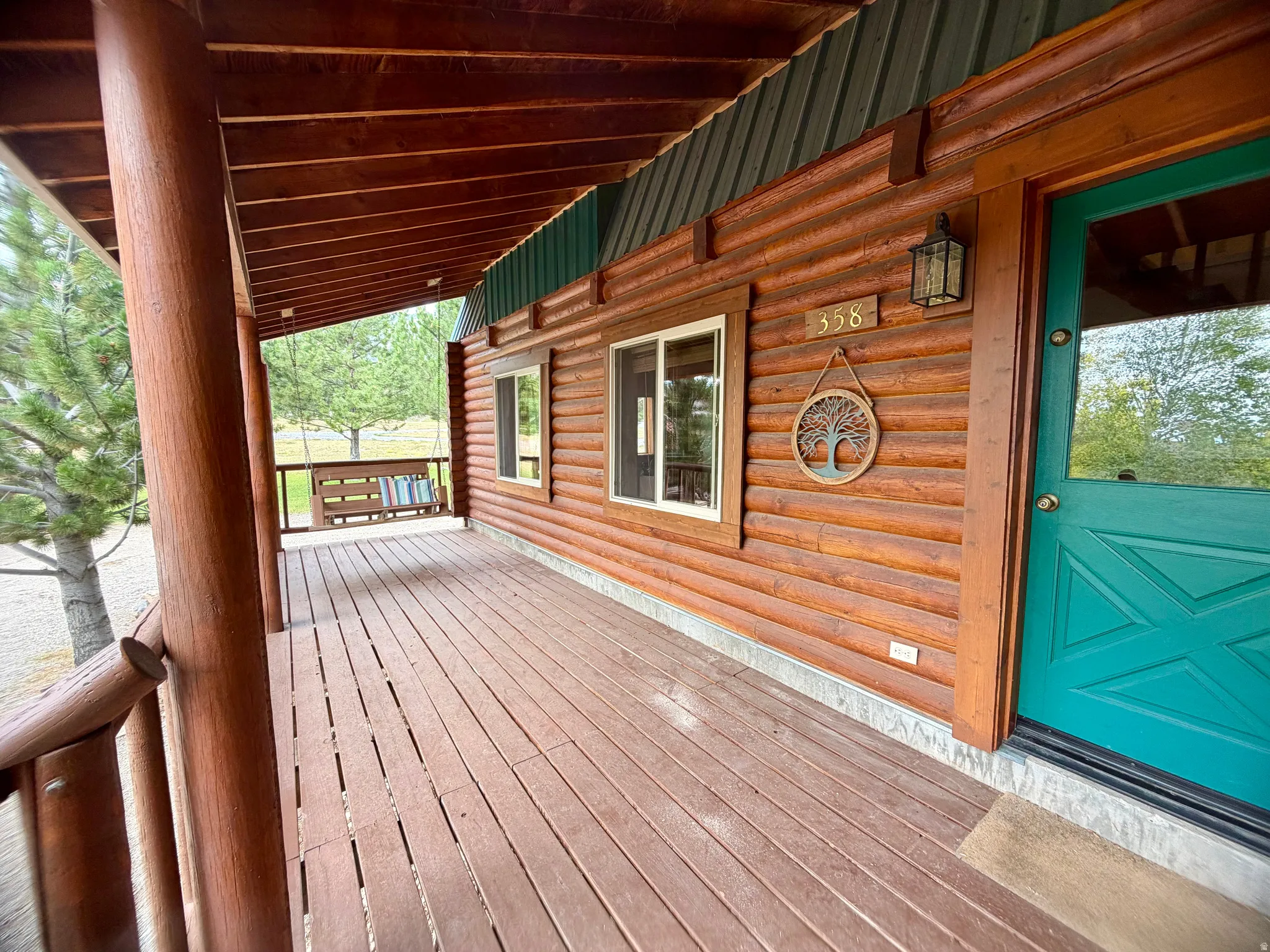 Front porch featuring wood plank flooring, log-style columns, a wood-paneled ceiling, and log cabin siding