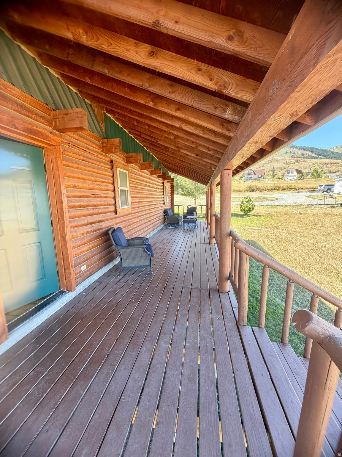 Expansive covered porch featuring wood-finish decking, log railings, and a wood-paneled ceiling