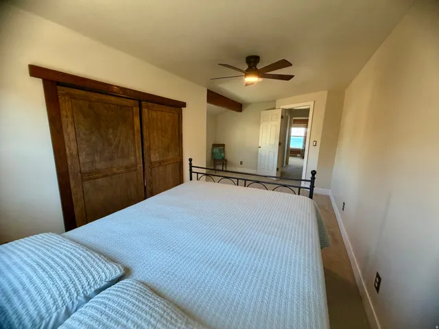 Recessed lighting, ceiling fan, wood-finish sliding closet doors, and wood-beam accents