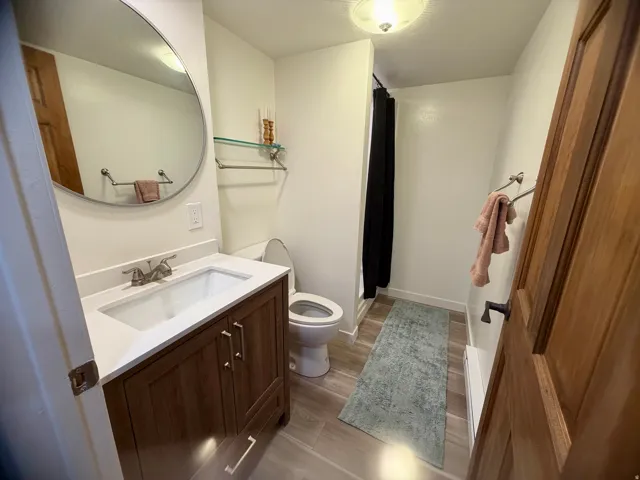 Bathroom featuring a wood-finish vanity with an integrated sink and light-toned countertop