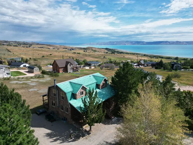 Distinctive brick residence featuring a striking turquoise metal roof, positioned on expansive grounds overlooking panoramic water vistas