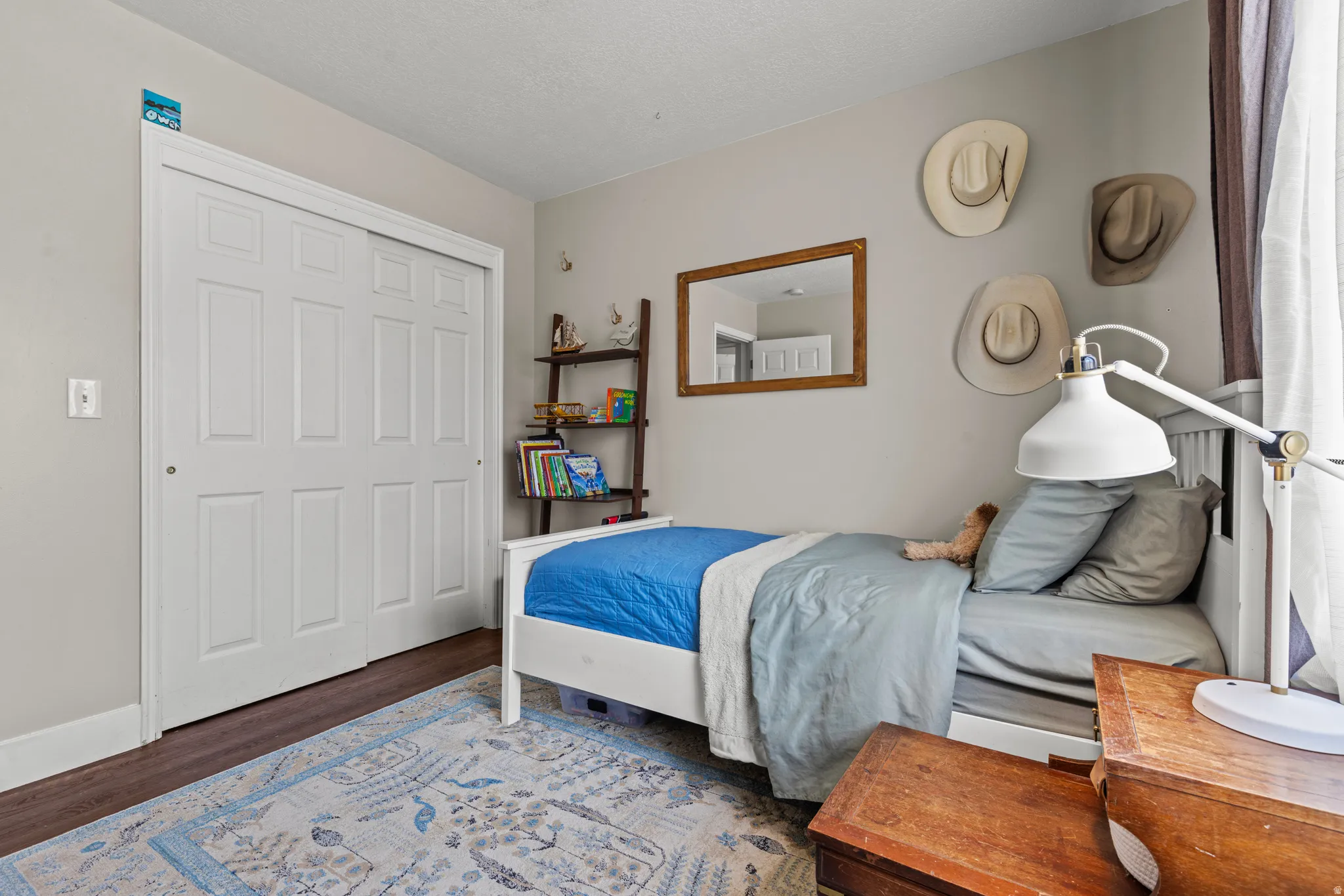 Bedroom featuring wood-finish flooring, light neutral wall paint, and a sliding door closet with six-panel doors