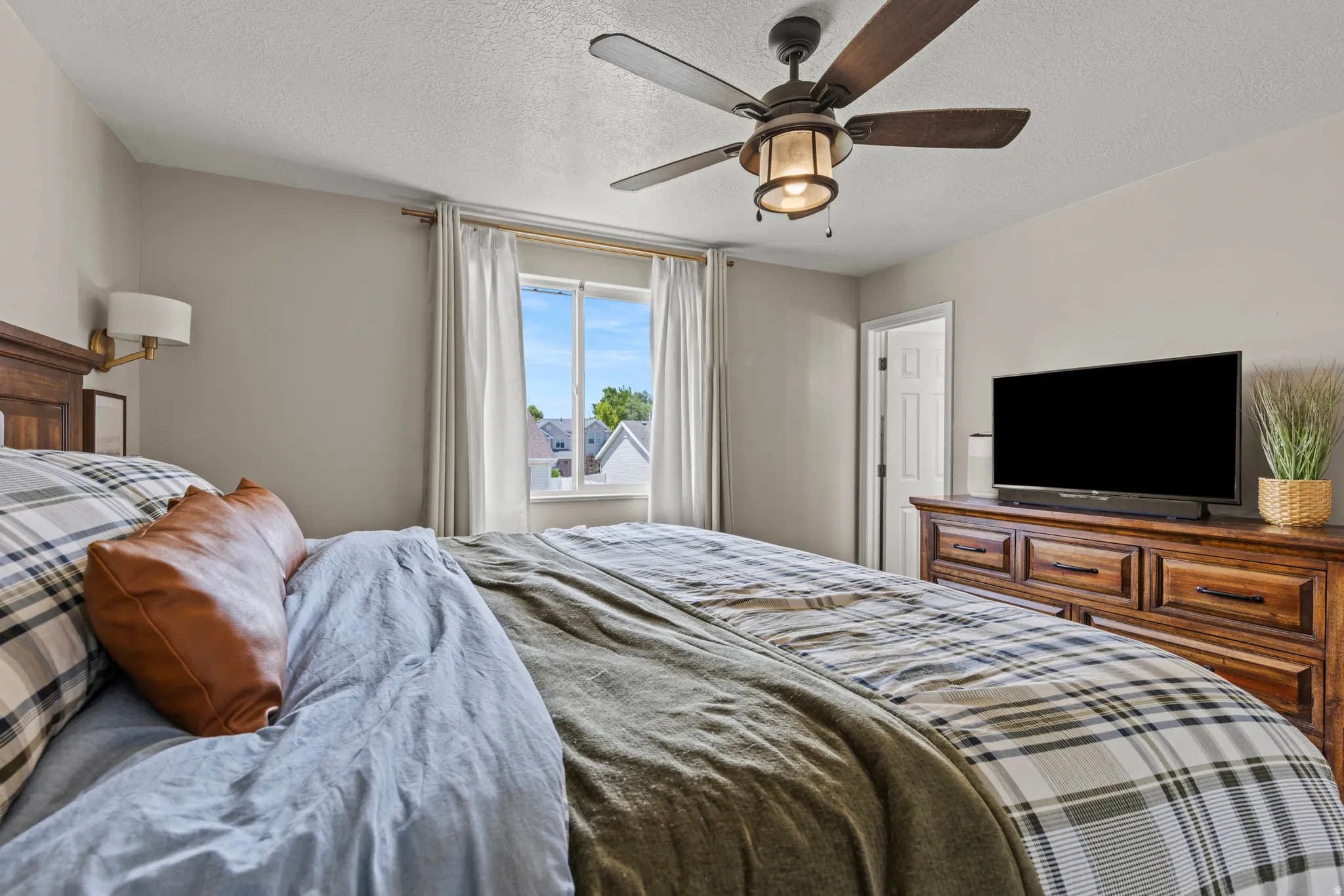 Bedroom featuring a window with natural light, a wood ceiling fan with integrated lighting, a built-in wall sconce, and a solid wood dresser