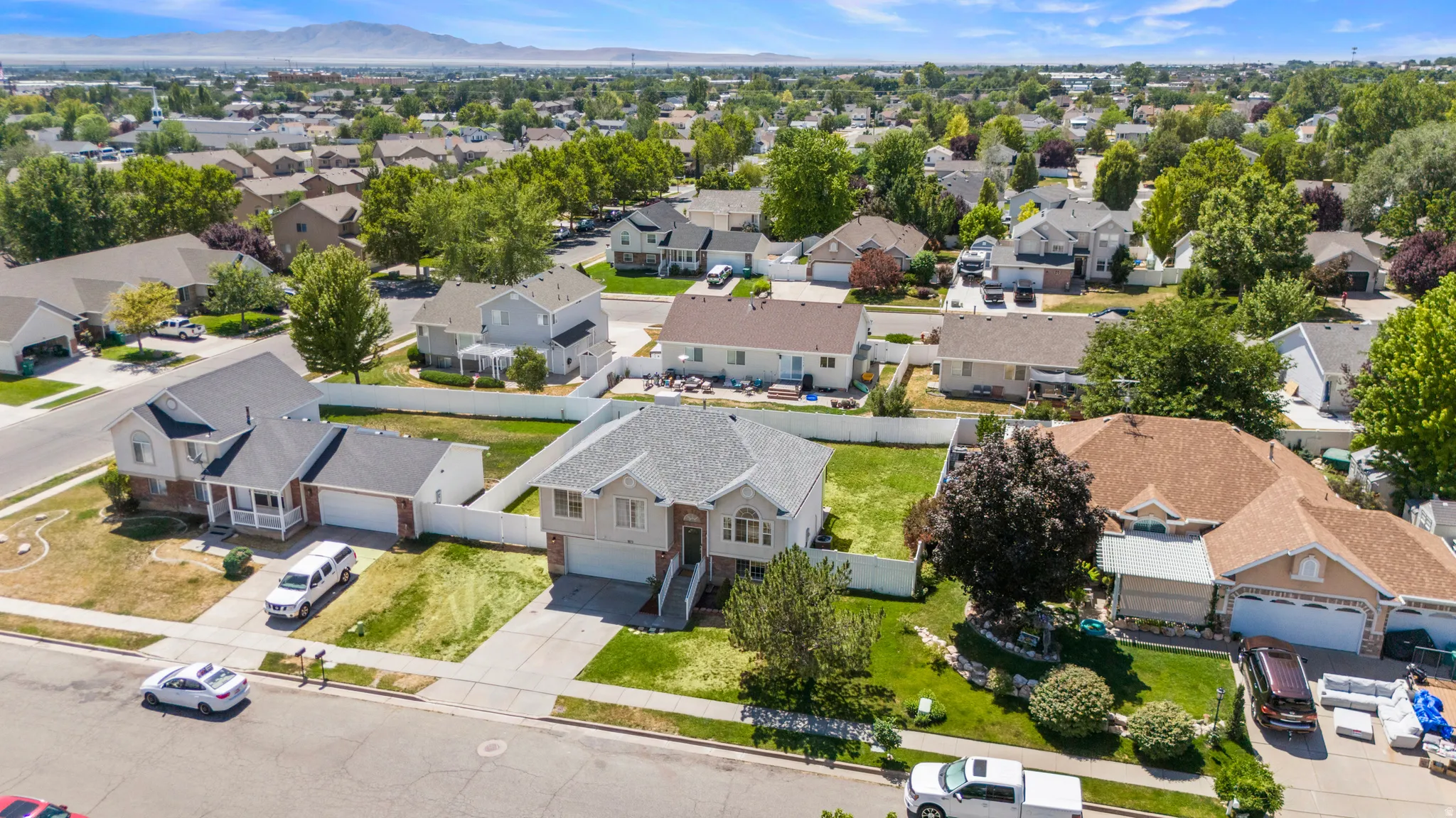 Suburban residential area featuring established homes, mature trees, and mountain scenery in the background