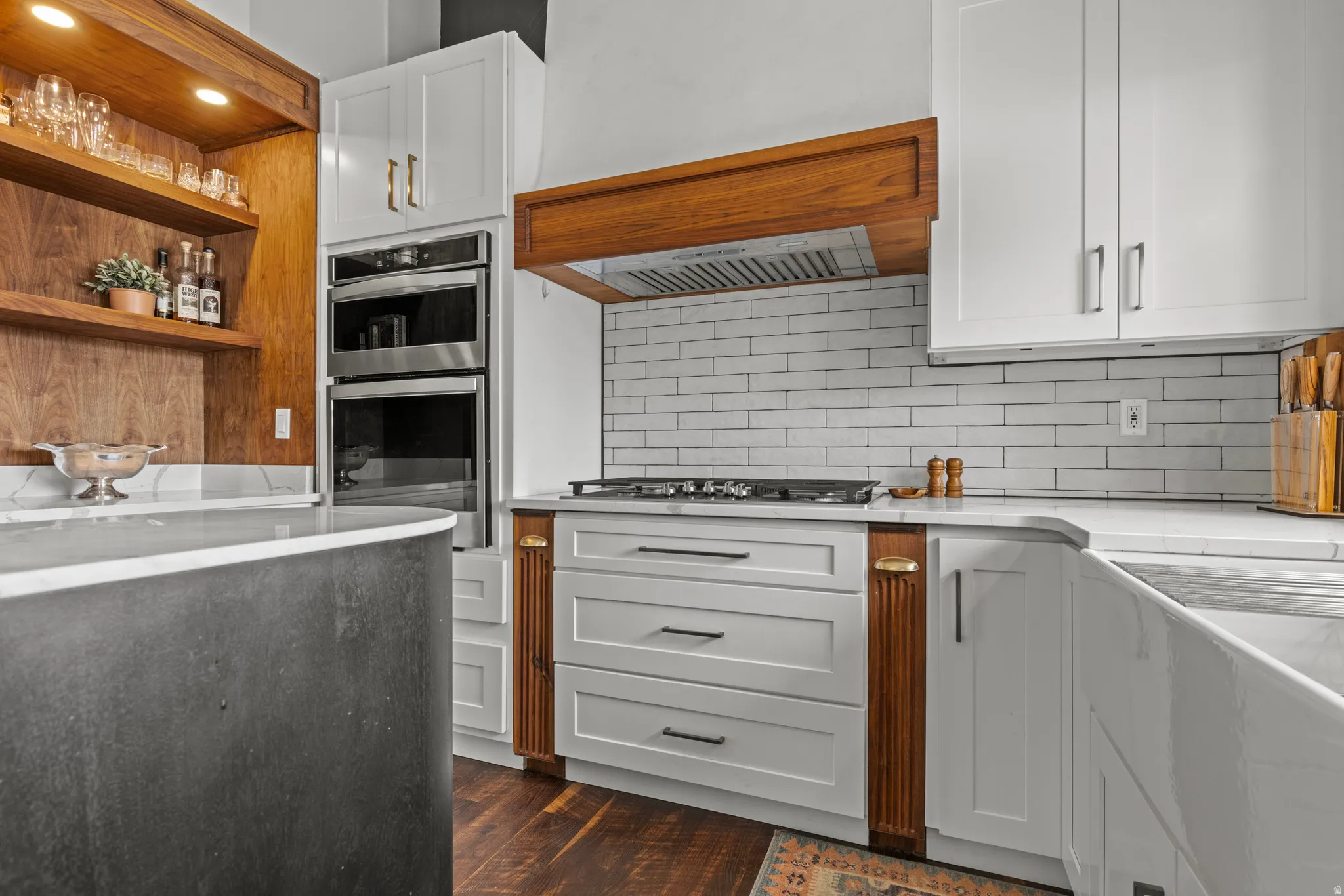 Contemporary kitchen featuring white cabinetry, integrated stainless steel double ovens, a built-in cooktop, and a white subway tile backsplash