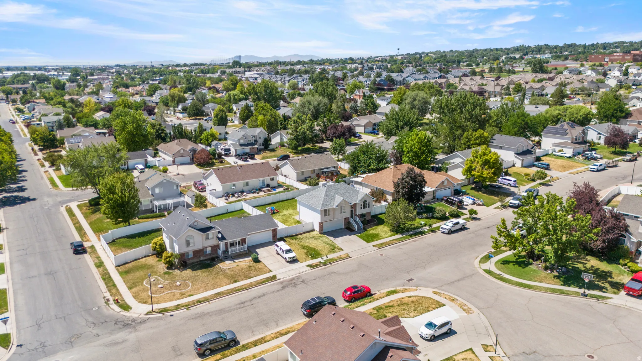 Aerial perspective showcasing residential neighborhood streets with numerous single-family homes, mature trees, and a distant mountain range