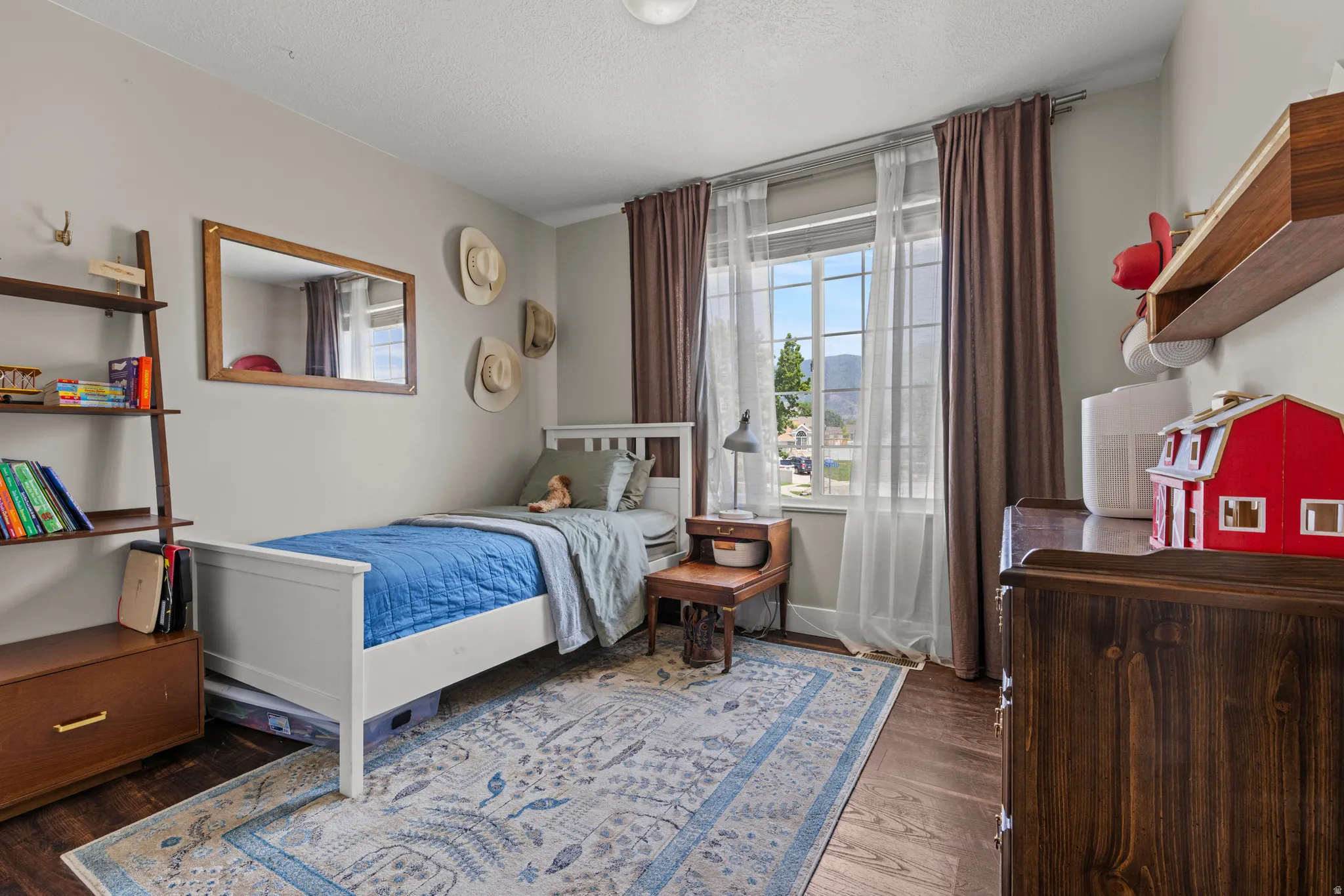 Bedroom featuring wood-finish flooring, a double-paned window with mountain scenery, and light gray wall paint