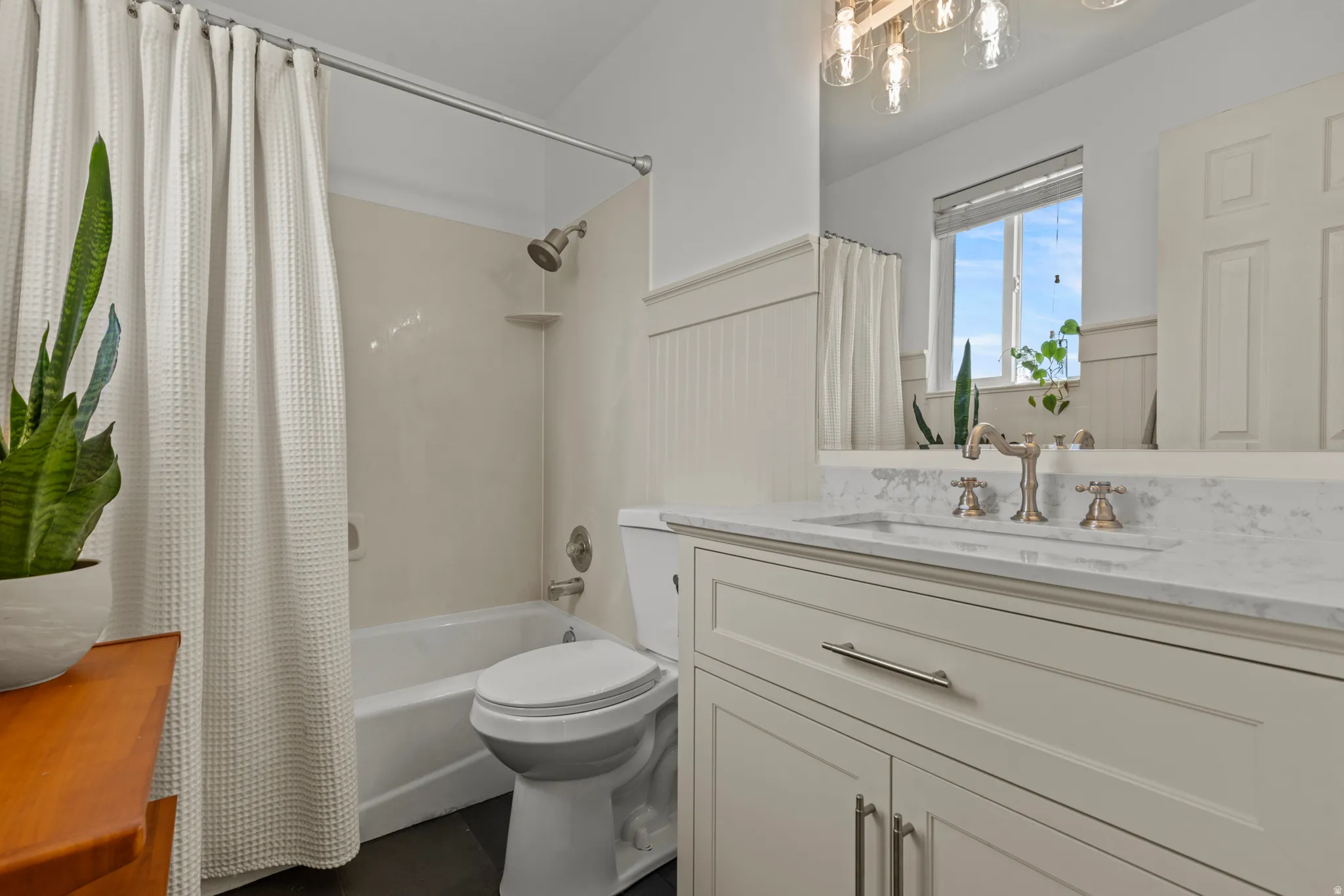 Bathroom featuring a tub and shower combination with a neutral surround, a white toilet, and dark floor tiling