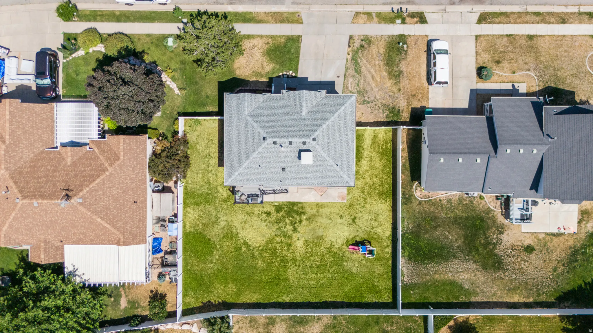 Aerial perspective showcasing a property with a gray shingle roof and a spacious, fenced backyard