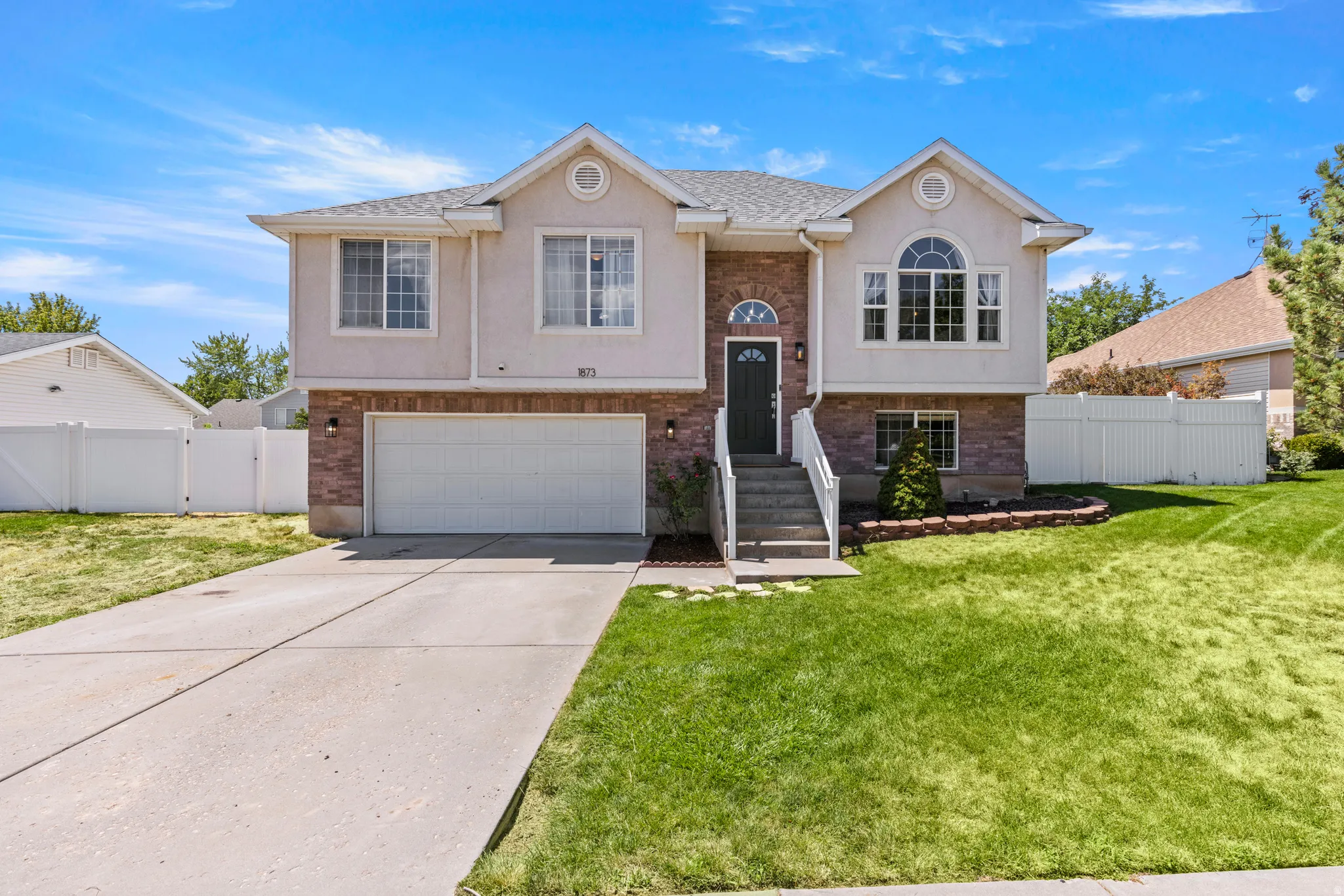 Two-story residence featuring a brick and stucco exterior, an arched window, an attached two-car garage, and a concrete driveway