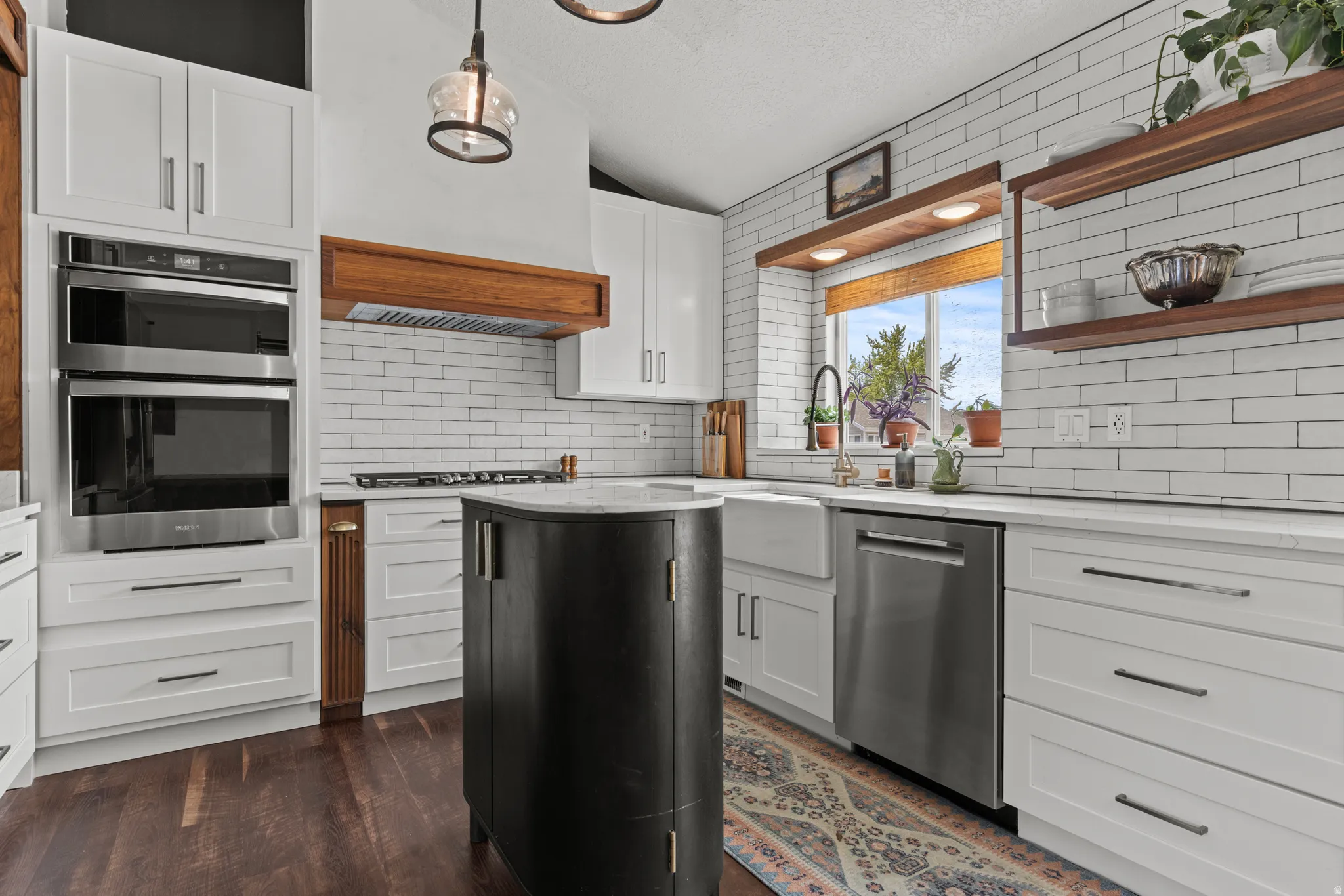 Modern kitchen featuring white shaker cabinetry, stainless steel appliances, a farmhouse-style sink, white subway tile backsplash, and wood-finish flooring