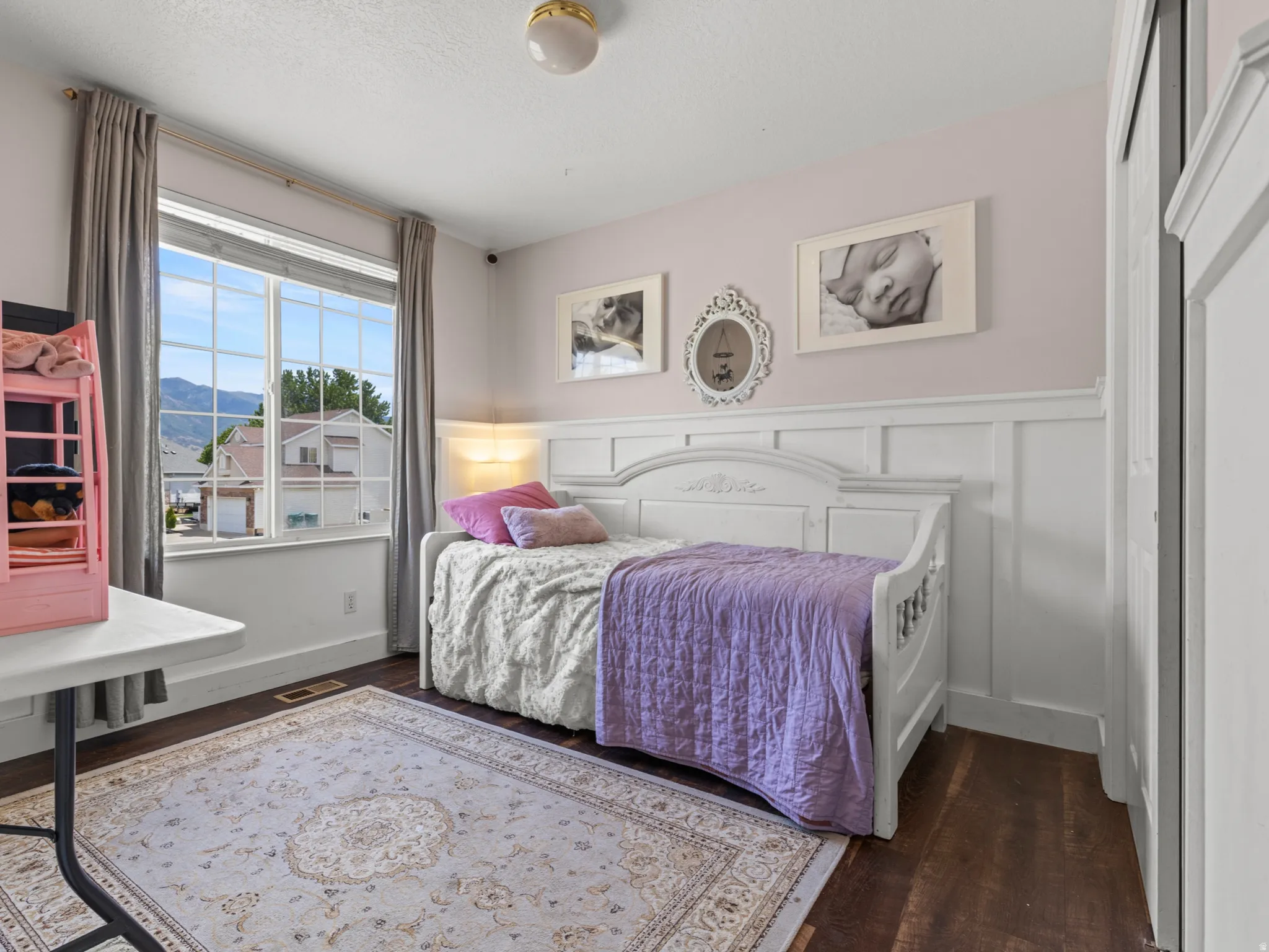 Room featuring a large window, board and batten wainscoting, wood-finish flooring, and a flush mount light fixture