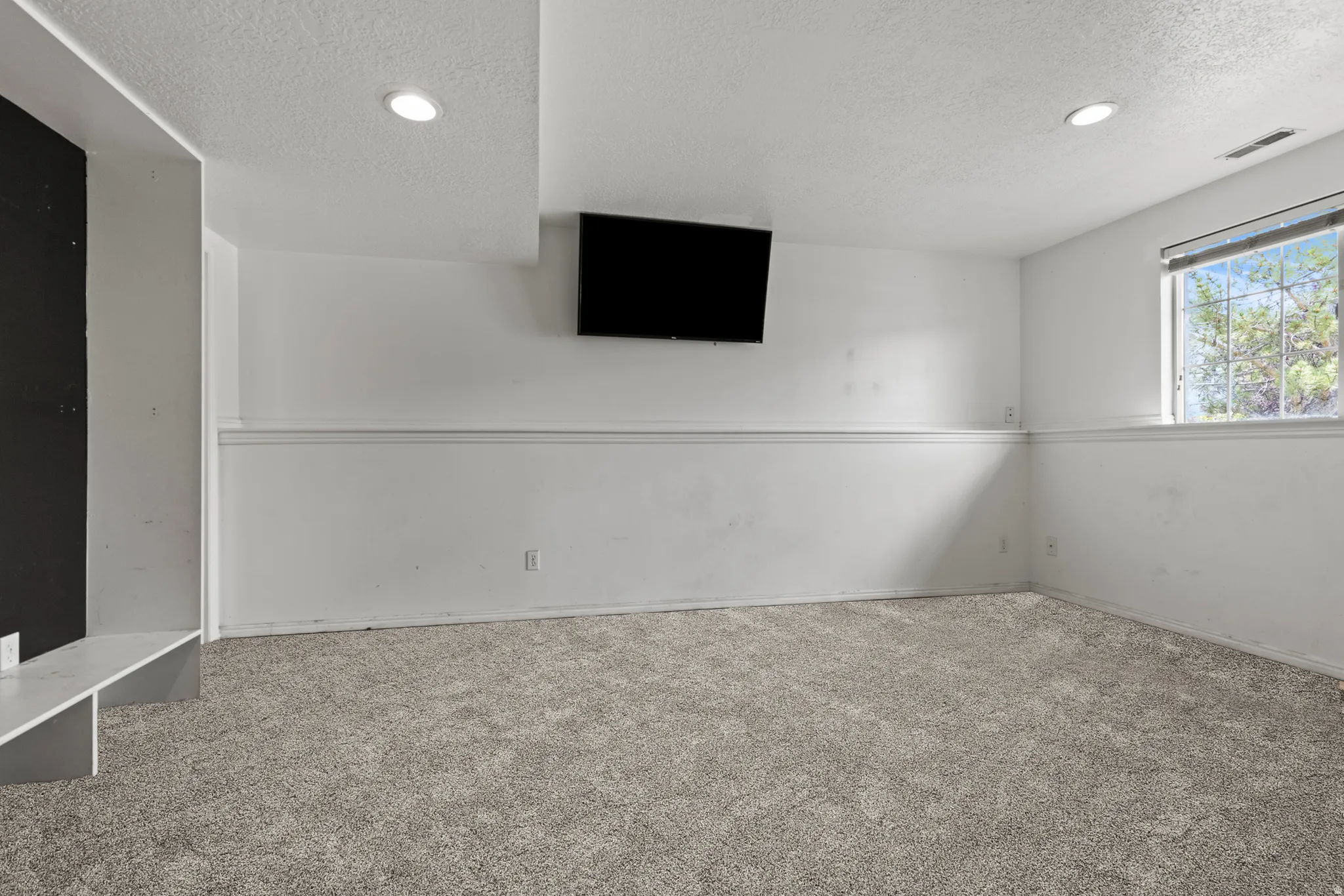 Spacious room featuring neutral carpet, white walls, recessed ceiling lighting, a built-in shelf, and natural light from a window. *Carpet is photoshopped in, ment to match new carpet.