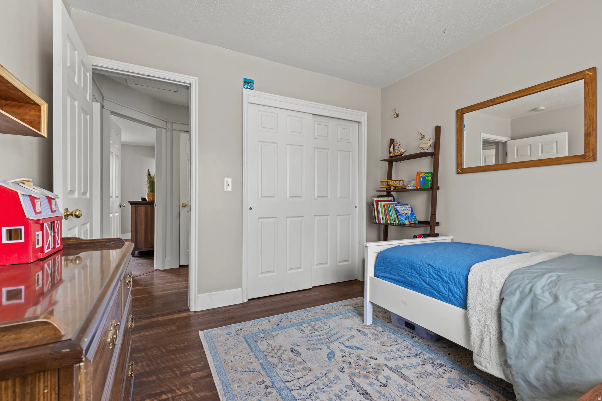 Spacious interior room featuring wood-finish flooring, light neutral wall paint, and white trim