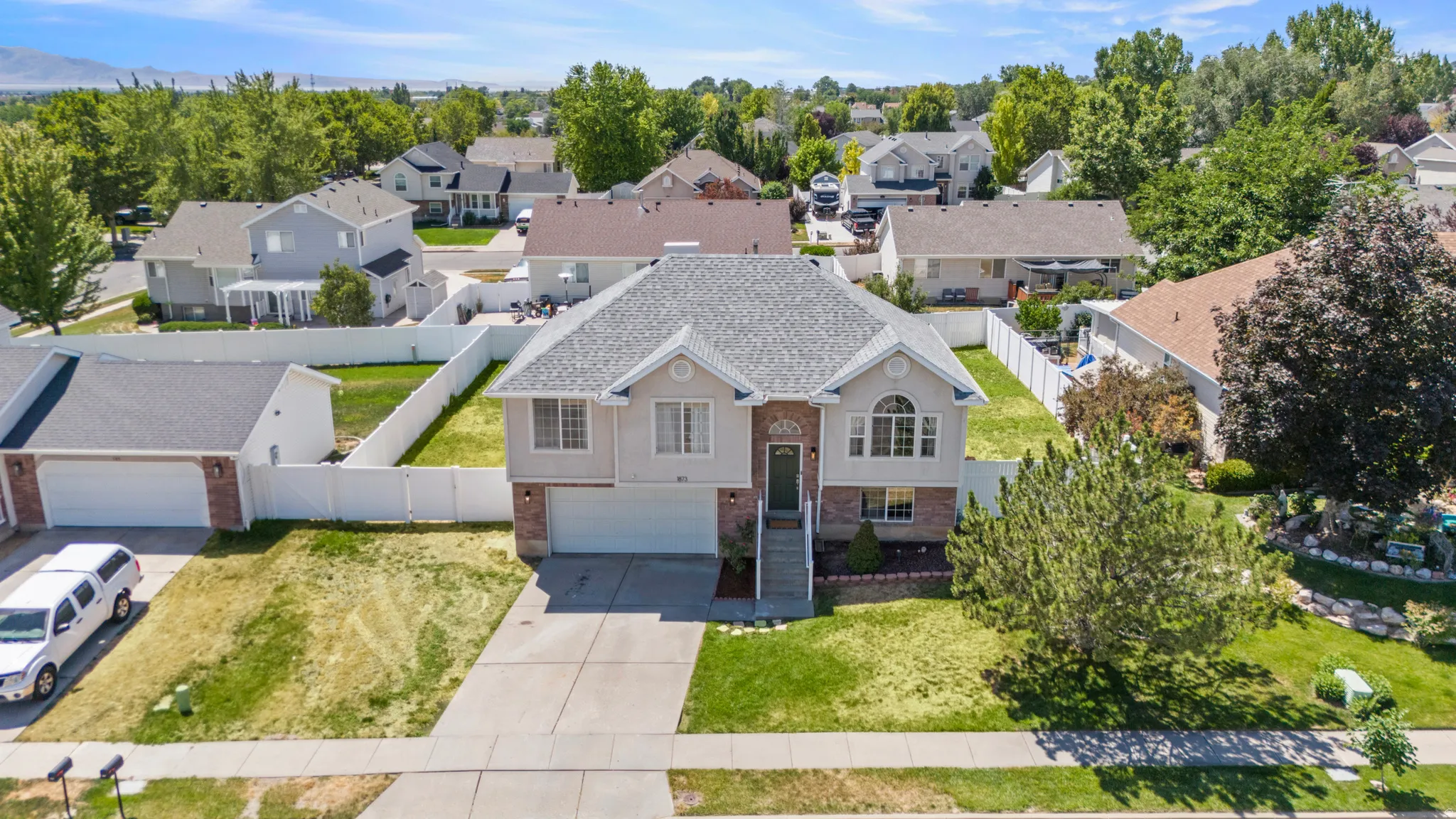Two-story residence featuring a two-car garage, brick facade accents, and a front yard with mature landscaping