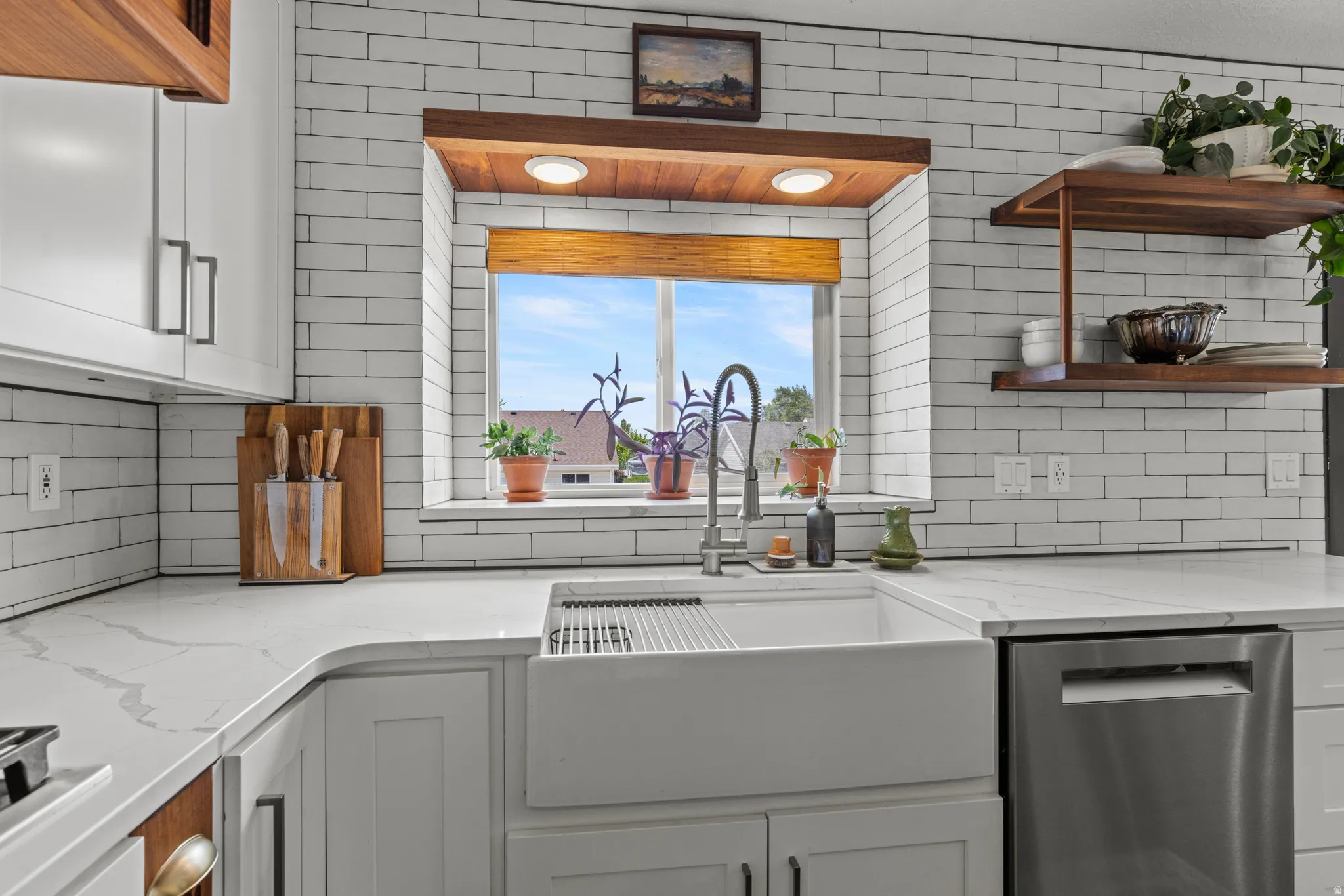 Kitchen featuring white shaker-style cabinetry, a farmhouse sink with a gooseneck faucet, and quartz countertops