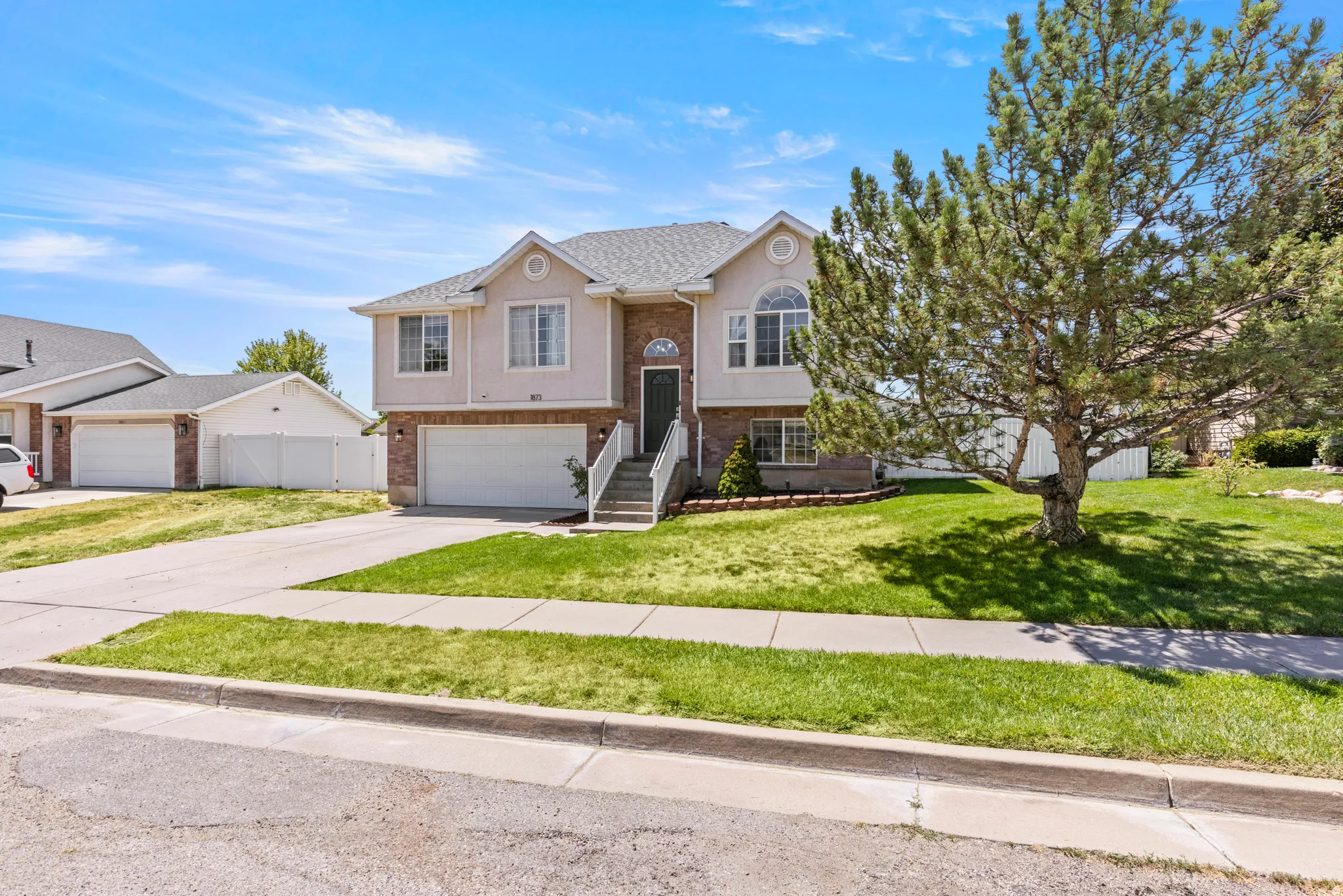 Two-story stucco and brick exterior featuring a multi-gable roofline, arched window, and dual garage doors