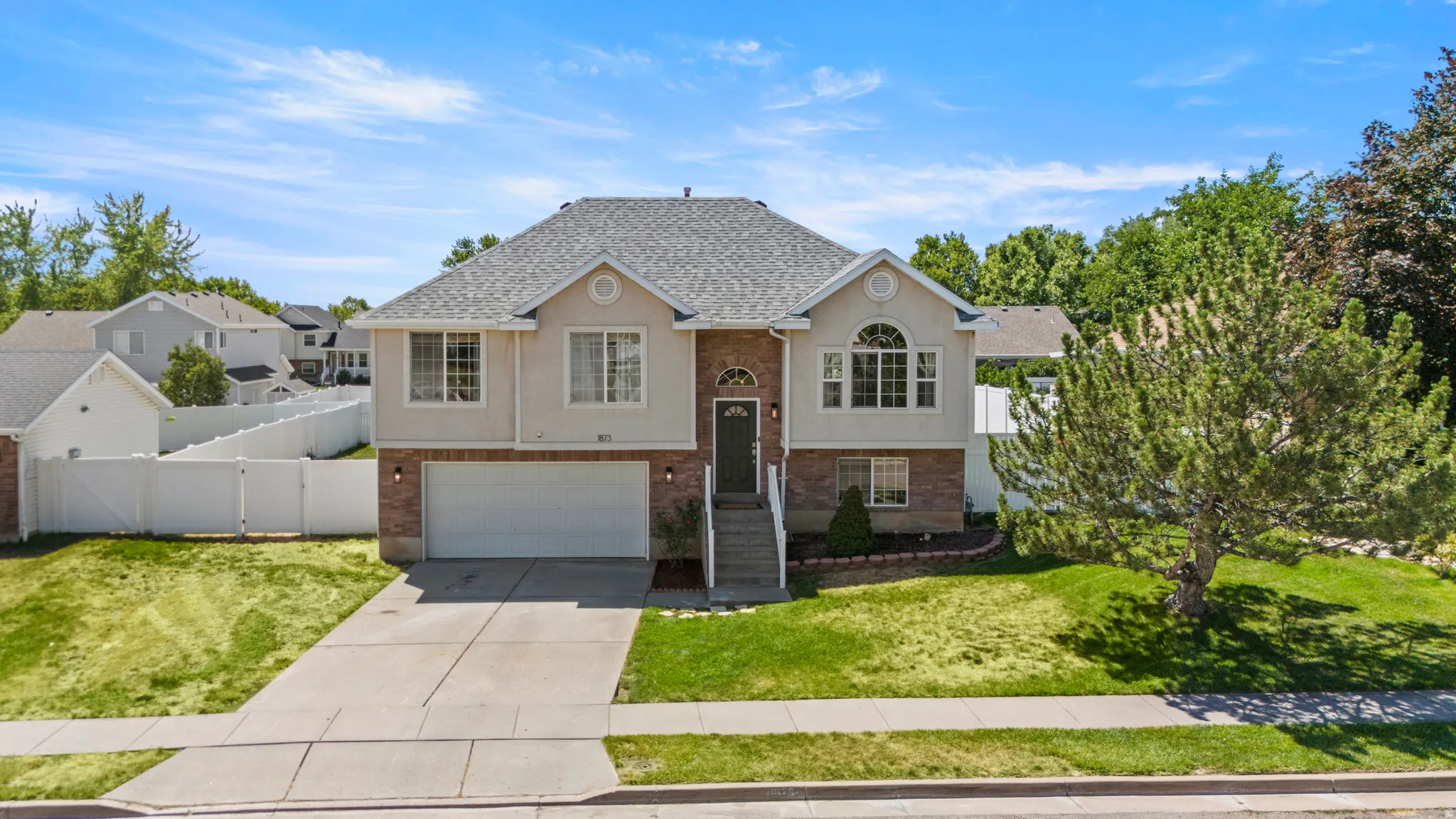 Two-story residential property featuring a gray shingle roof, light-colored siding, and brick accents