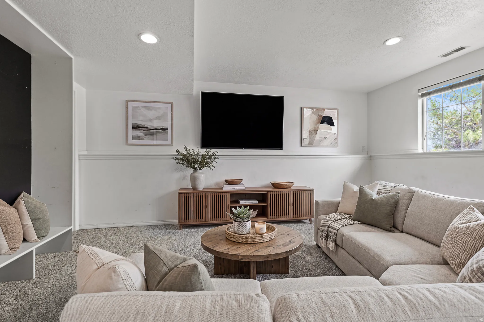 Virtually Staged family room featuring recessed lighting, a window with natural light, textured carpeting, and a built-in media wall with white wainscoting. *Carpet is photoshopped in, ment to match new carpet.