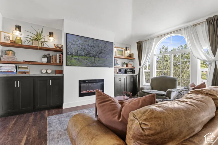 Spacious living area featuring wood-finish flooring, an arched window, and a built-in electric fireplace