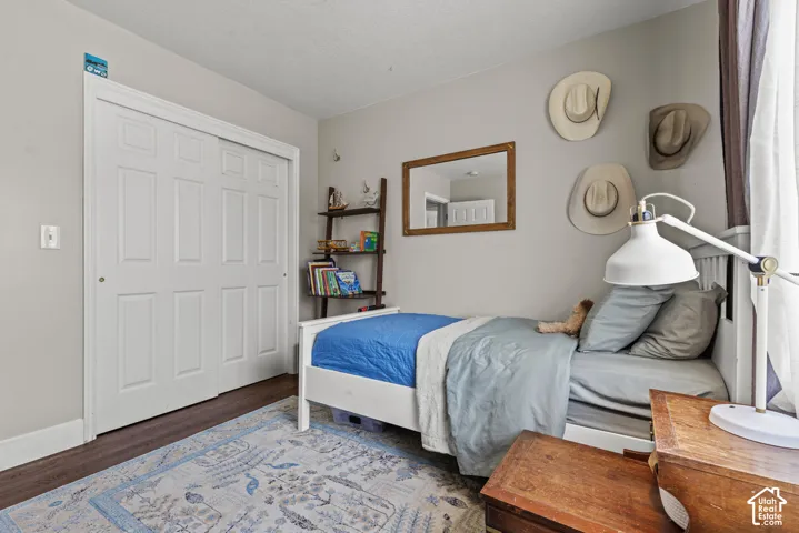 Bedroom featuring wood-finish flooring, light neutral wall paint, and a sliding door closet with six-panel doors