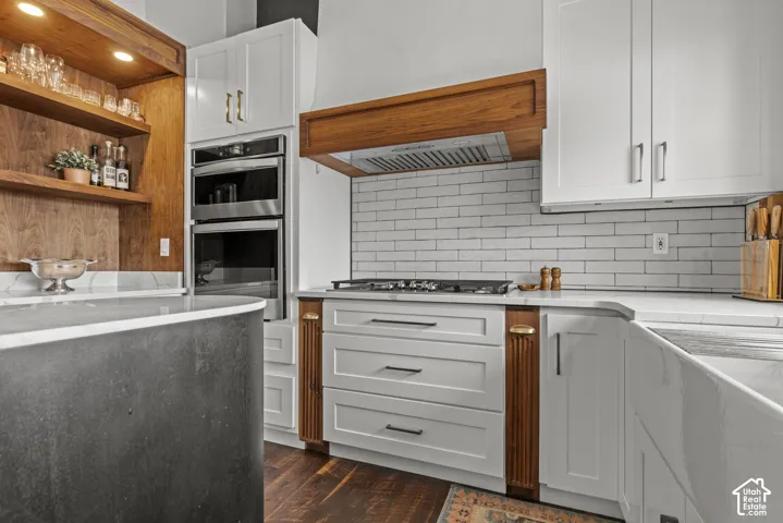 Contemporary kitchen featuring white cabinetry, integrated stainless steel double ovens, a built-in cooktop, and a white subway tile backsplash
