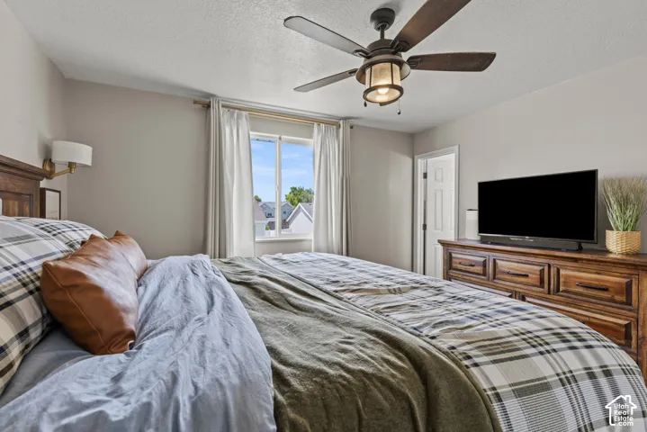 Bedroom featuring a window with natural light, a wood ceiling fan with integrated lighting, a built-in wall sconce, and a solid wood dresser