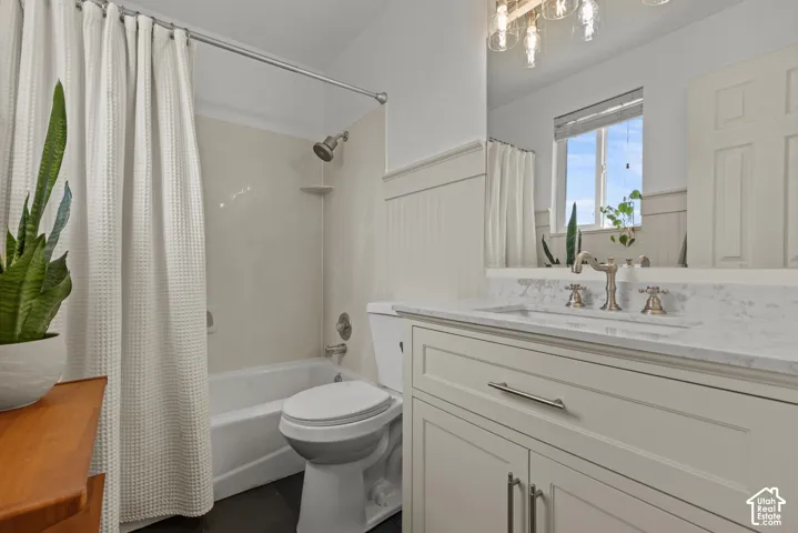 Bathroom featuring a tub and shower combination with a neutral surround, a white toilet, and dark floor tiling