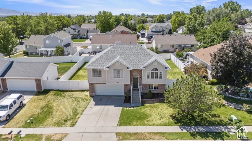 Two-story residence featuring a two-car garage, brick facade accents, and a front yard with mature landscaping