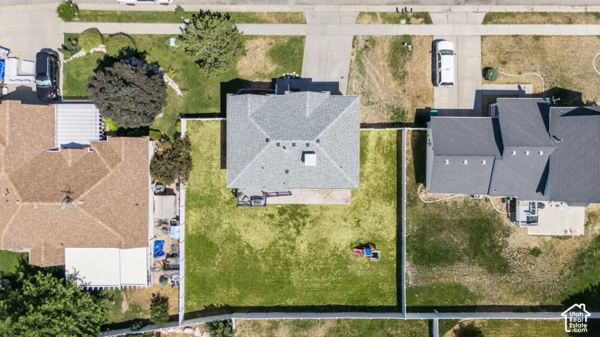 Aerial perspective showcasing a property with a gray shingle roof and a spacious, fenced backyard