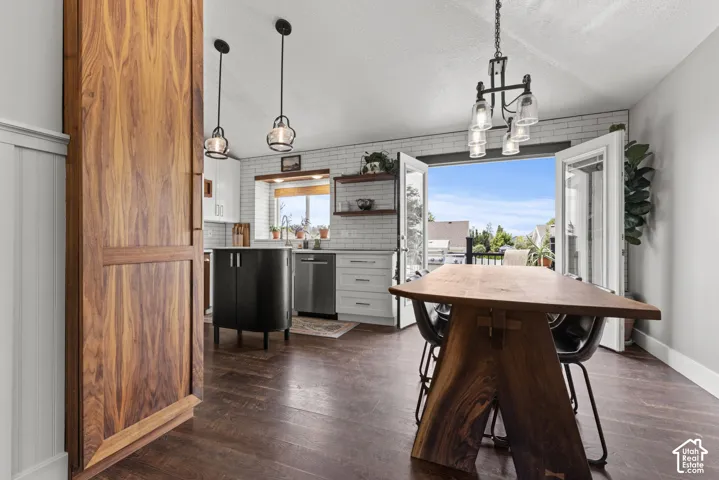 Open-concept dining and kitchen area featuring wood-finish flooring, a wood barn door, and a kitchen with white subway tile backsplash and stainless steel appliances