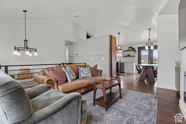 Open-concept living area featuring vaulted ceilings, dark wood-finish flooring, and a modern black metal railing
