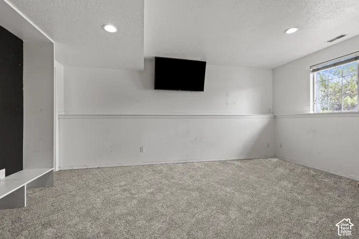 Spacious room featuring neutral carpet, white walls, recessed ceiling lighting, a built-in shelf, and natural light from a window. *Carpet is photoshopped in, ment to match new carpet.