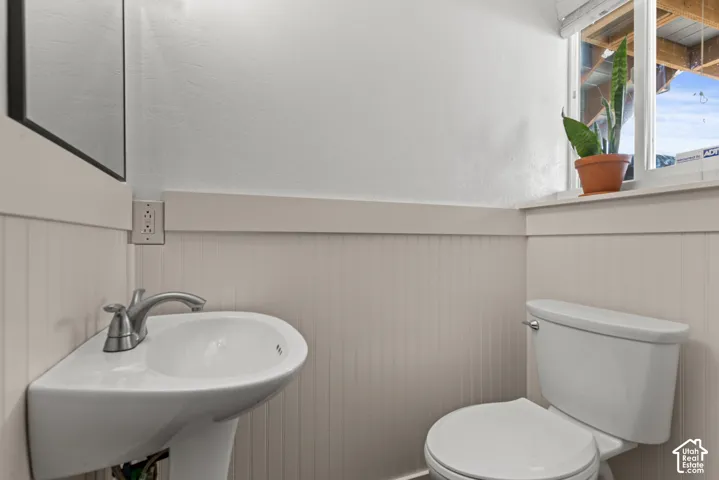 Pedestal sink with chrome faucet, toilet, and beadboard wainscoting