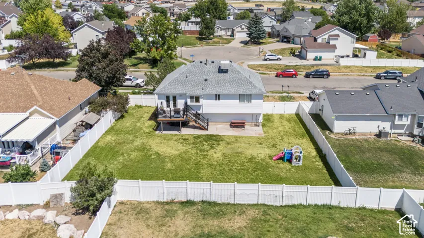 Expansive fenced backyard with a manicured lawn, an elevated deck, and a lower patio area